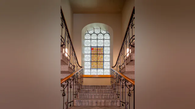 De gerenoveerde hoofdtrap, waar beide ingangen naartoe leiden, inclusief een herdenkenis van de Tweede Wereldoorlog in glas-in-lood. Beeld Lucas van der Wee