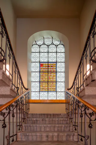 De gerenoveerde hoofdtrap, waar beide ingangen naartoe leiden, inclusief een herdenkenis van de Tweede Wereldoorlog in glas-in-lood. Beeld Lucas van der Wee