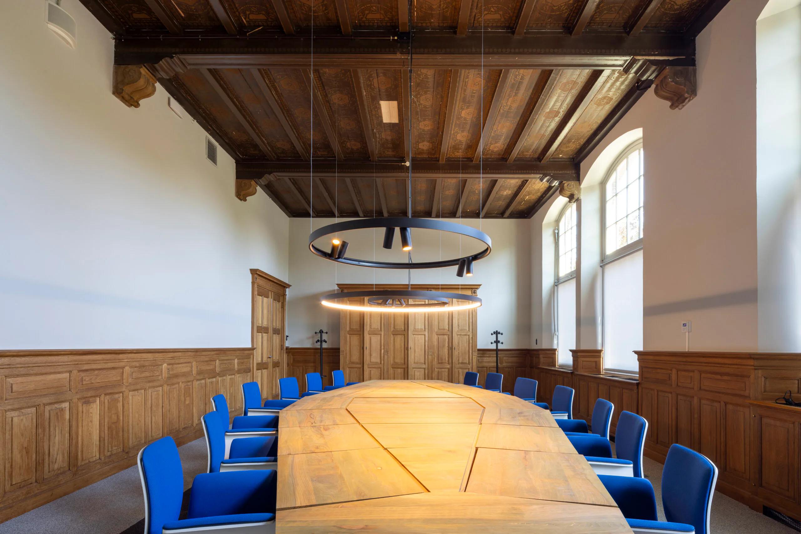 Alles in het kantoor staat in dienst van een verhaal, van de gerenoveerde plafonds en lambrisering tot houten tafelbladen, gemaakt van de gekapte bomen uit de atria. Beeld door Lucas van der Wee