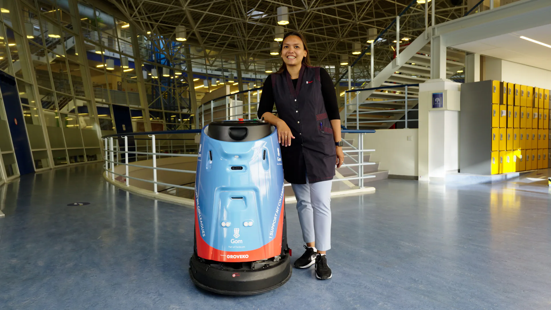 Een medewerker van GOM bij de robot die haar niet vervangt maar haar juist ondersteunt bij het werk.